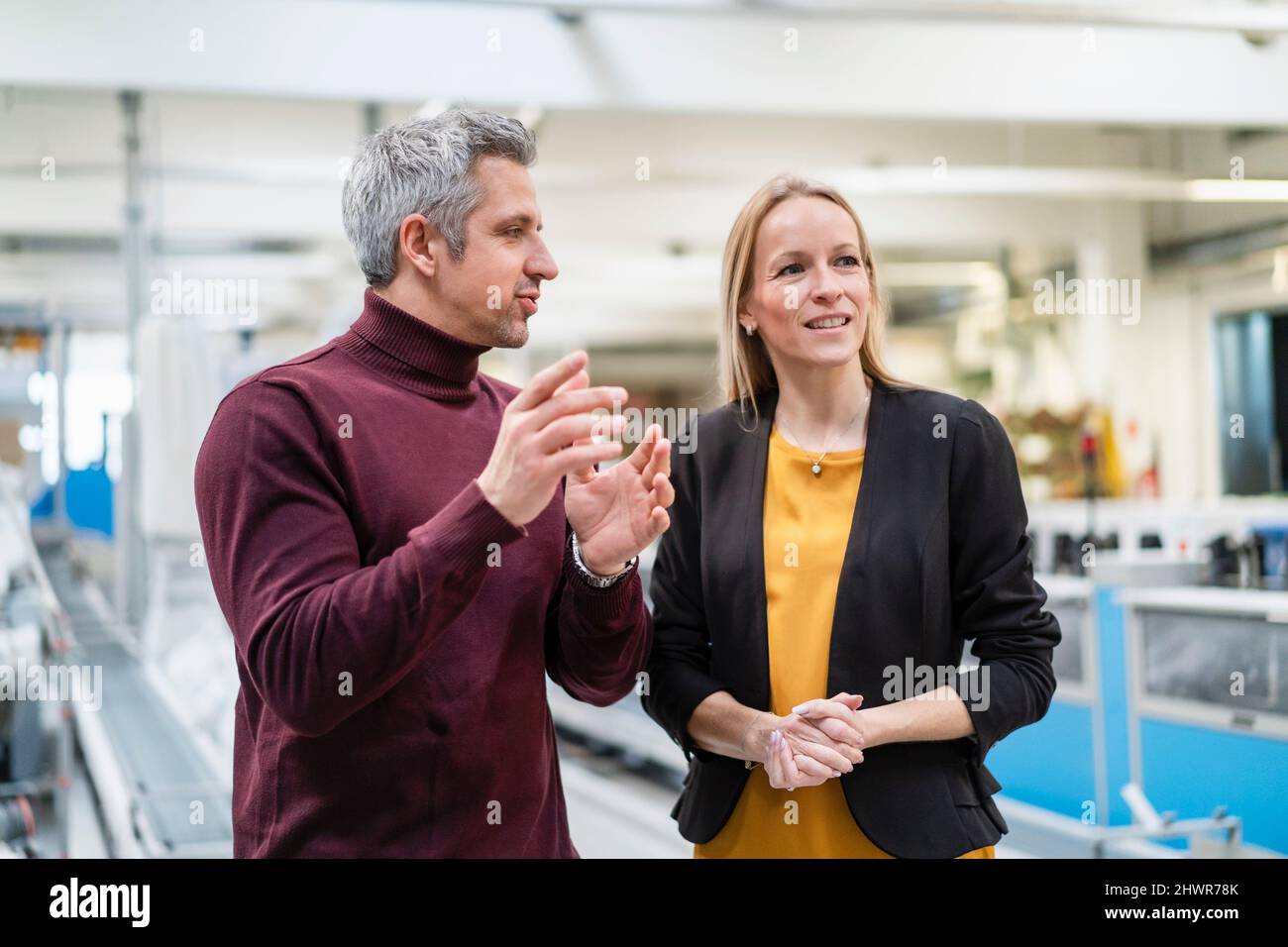 Uomo d'affari che condivide le idee con la donna d'affari bionda nell'industria Foto Stock