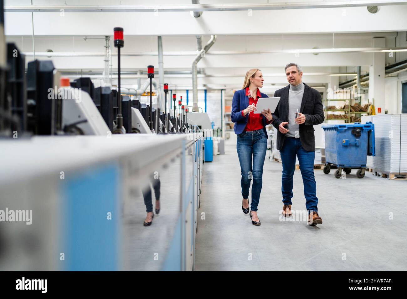 Uomo d'affari e donna d'affari che condividono idee che camminano nel muro di produzione Foto Stock