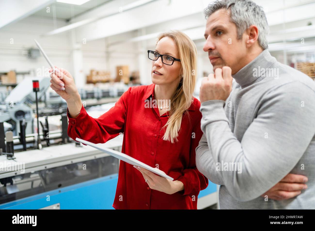 Donna d'affari bionda con PC tablet che condivide idee con colleghi del settore Foto Stock