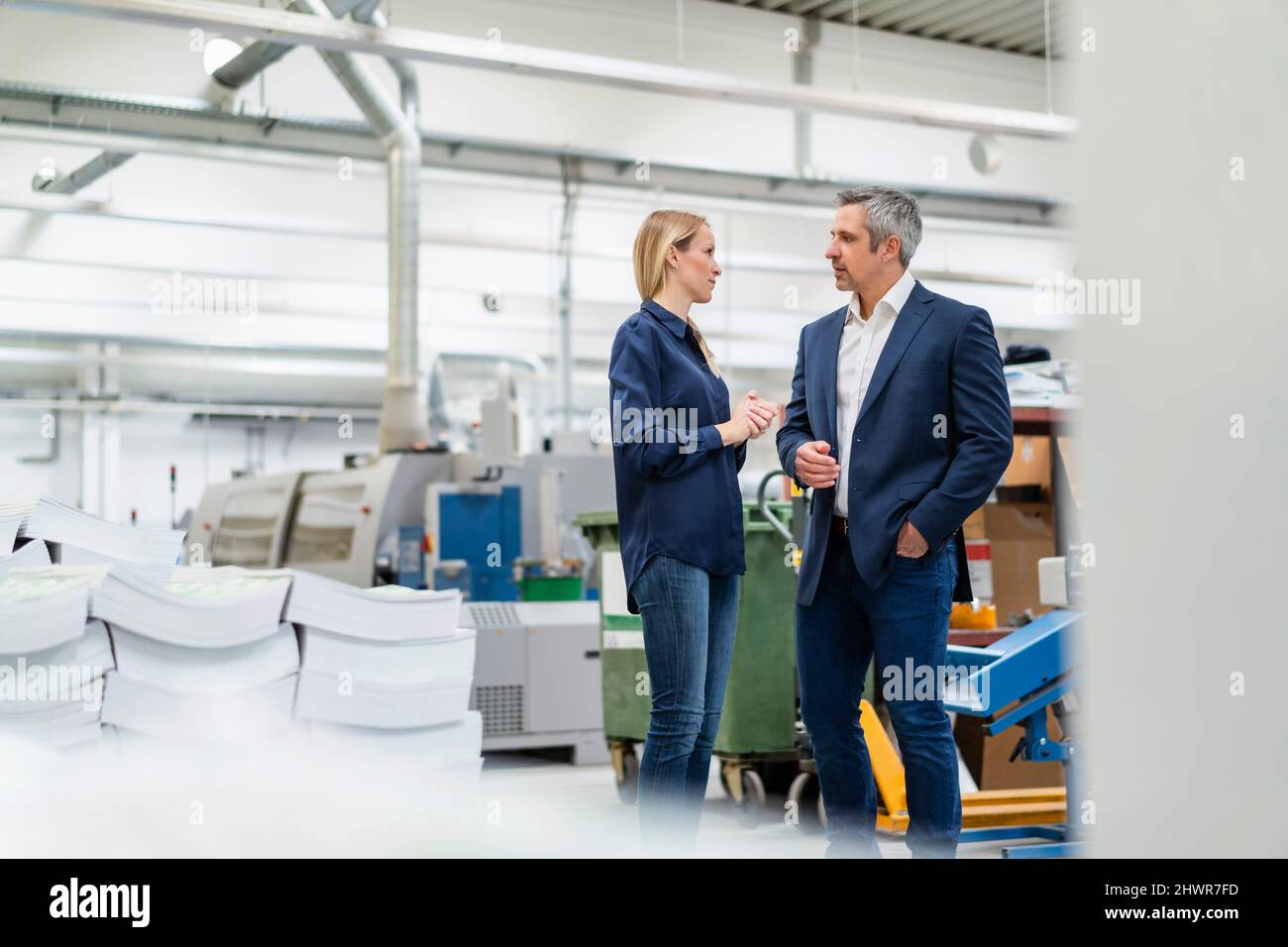 Donna d'affari bionda che discute le idee con il collega nell'industria Foto Stock