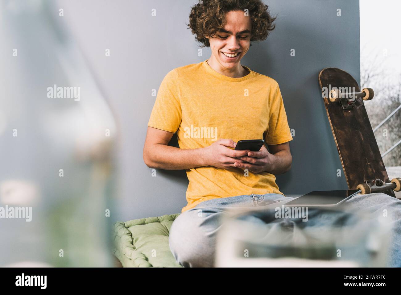 Messaggi di testo Happy MAN tramite smartphone da skateboard a casa Foto Stock