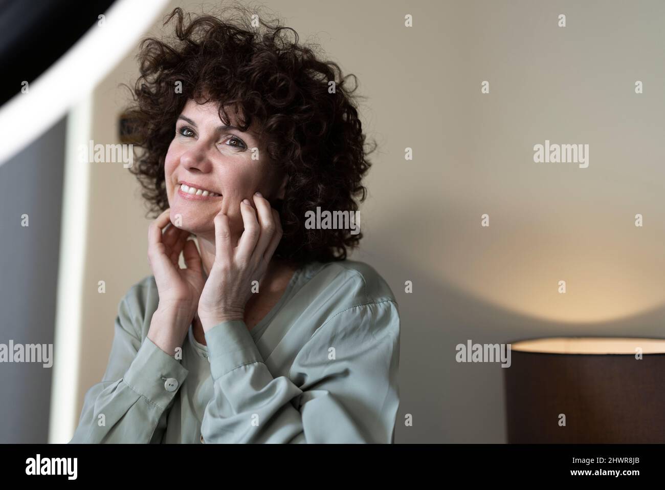 Vlogger sorridente che tocca le guance a casa Foto Stock