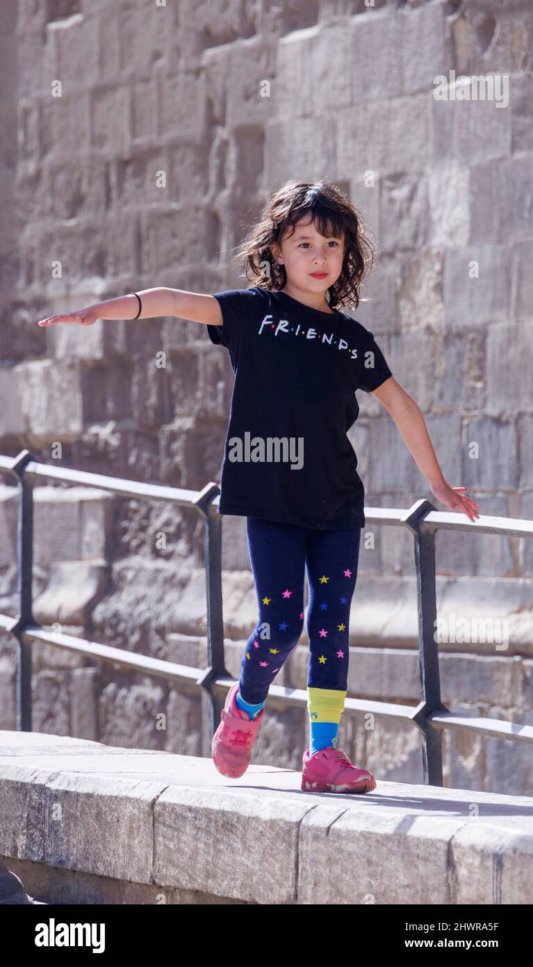 giovane ragazza che cammina lungo il muro concentrandosi sull'equilibrio Foto Stock