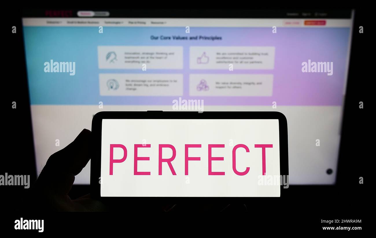 Persona che tiene smartphone con il logo della società taiwanese Beauty Tech Perfect Corp. Sullo schermo di fronte al sito web. Mettere a fuoco sul display del telefono. Foto Stock