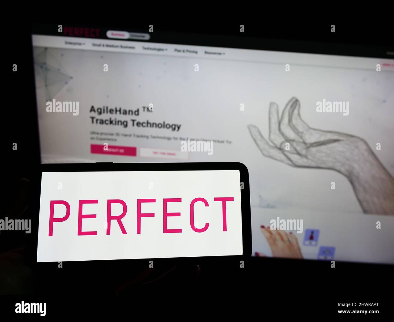 Persona che tiene il cellulare con il logo della società taiwanese di tecnologia di bellezza Perfect Corp. Sullo schermo di fronte al Web site di affari. Mettere a fuoco sul display del telefono. Foto Stock