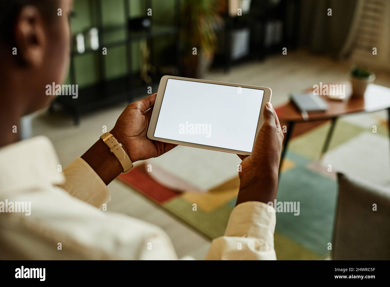 Primo piano di una giovane donna nera che tiene un tablet con schermo vuoto durante il funzionamento dei dispositivi per la casa intelligente, spazio di copia Foto Stock