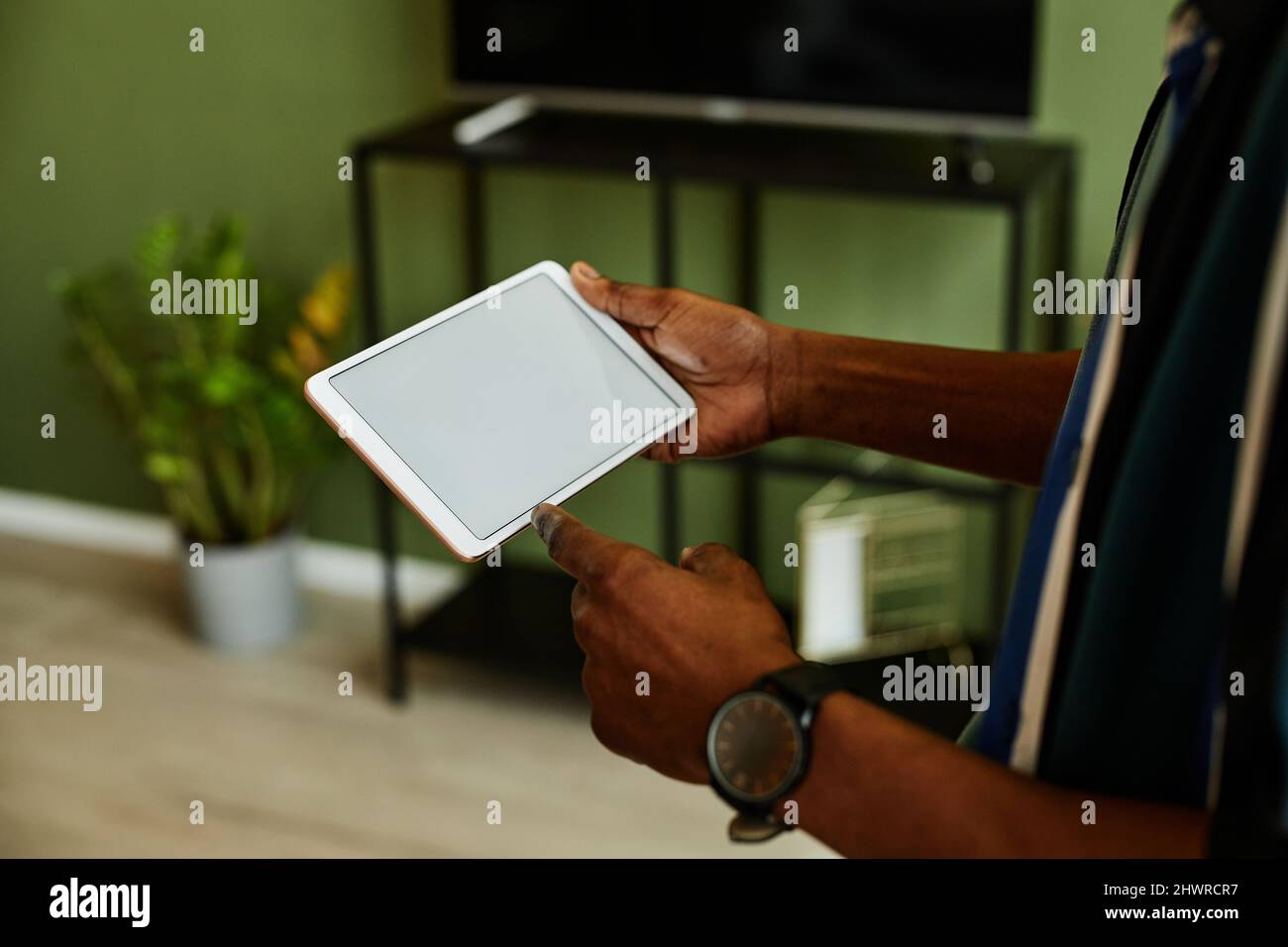 Primo piano di un giovane nero che tiene il tablet con schermo vuoto durante il funzionamento dei dispositivi per la casa intelligente, spazio di copia Foto Stock