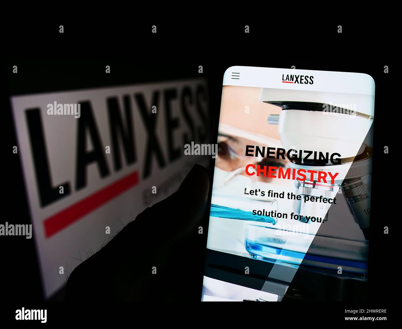 Persona che tiene lo smartphone con il sito web della società chimica tedesca Lanxess AG sullo schermo di fronte al logo. Concentrarsi sul centro del display del telefono. Foto Stock