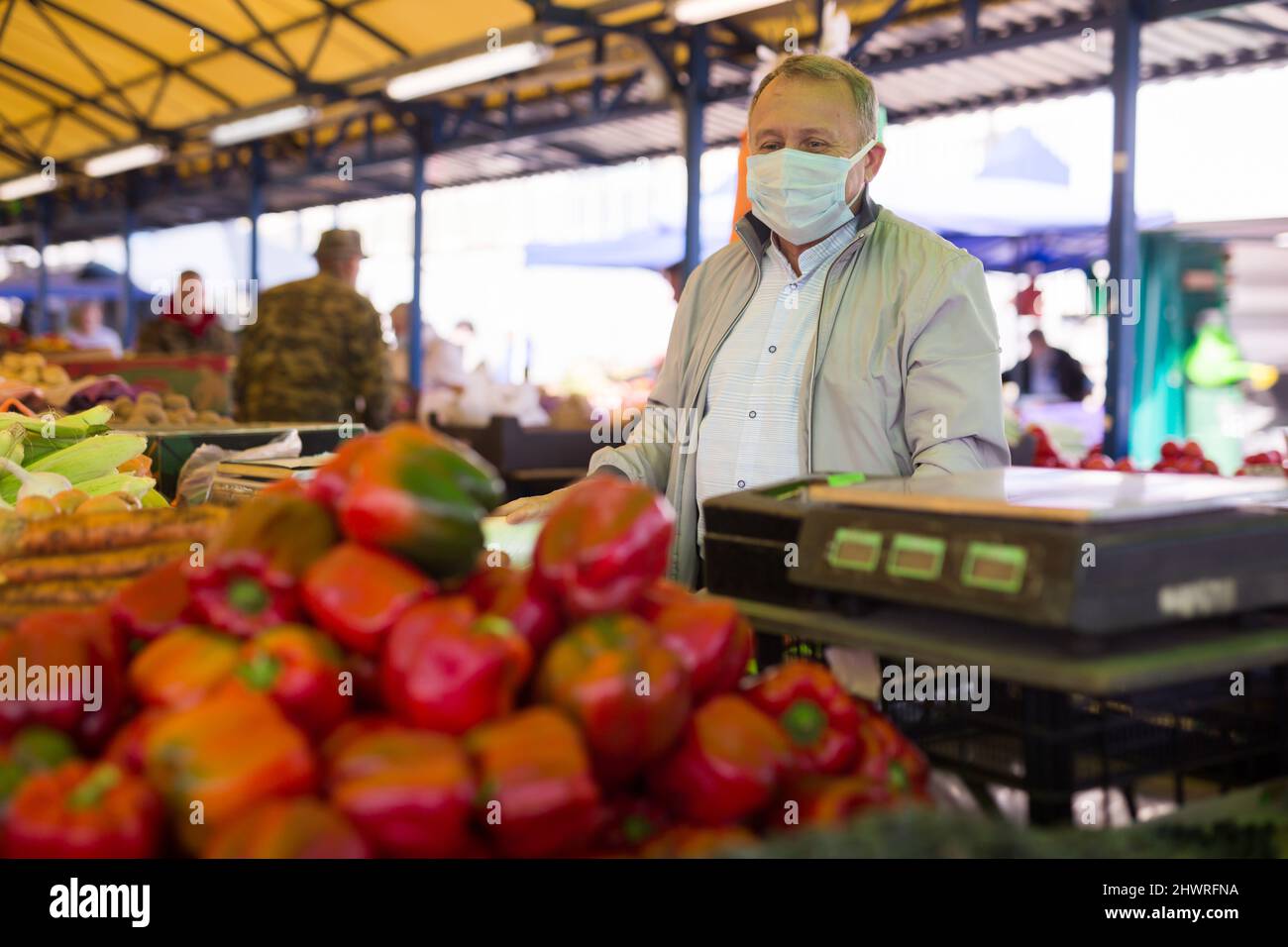 Uomo in maschera acquistare pepe nel mercato Foto Stock