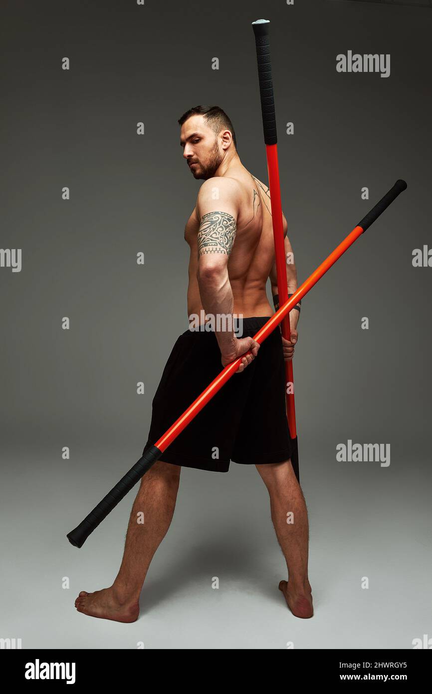atleta con allenatore bastone karate utilizzando lo strumento sportivo in  studio su sfondo grigio luci Foto stock - Alamy