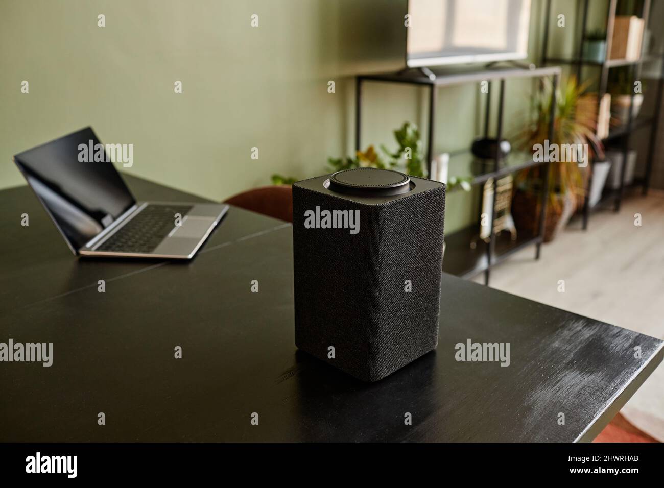 Immagine di sfondo di un altoparlante intelligente con sistema di Home ai con controllo vocale su un tavolo nero, spazio di copia Foto Stock