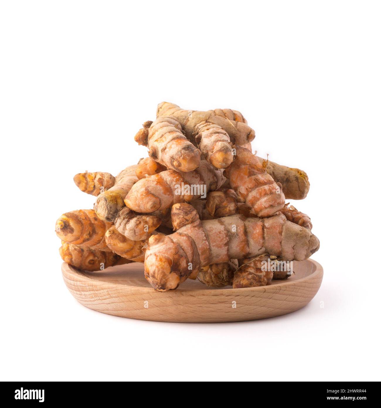 radici curmeriche, tradizionale spezia del sud-est asiatico su un piatto di legno, noto anche per scopi medicinali, isolato su sfondo bianco Foto Stock