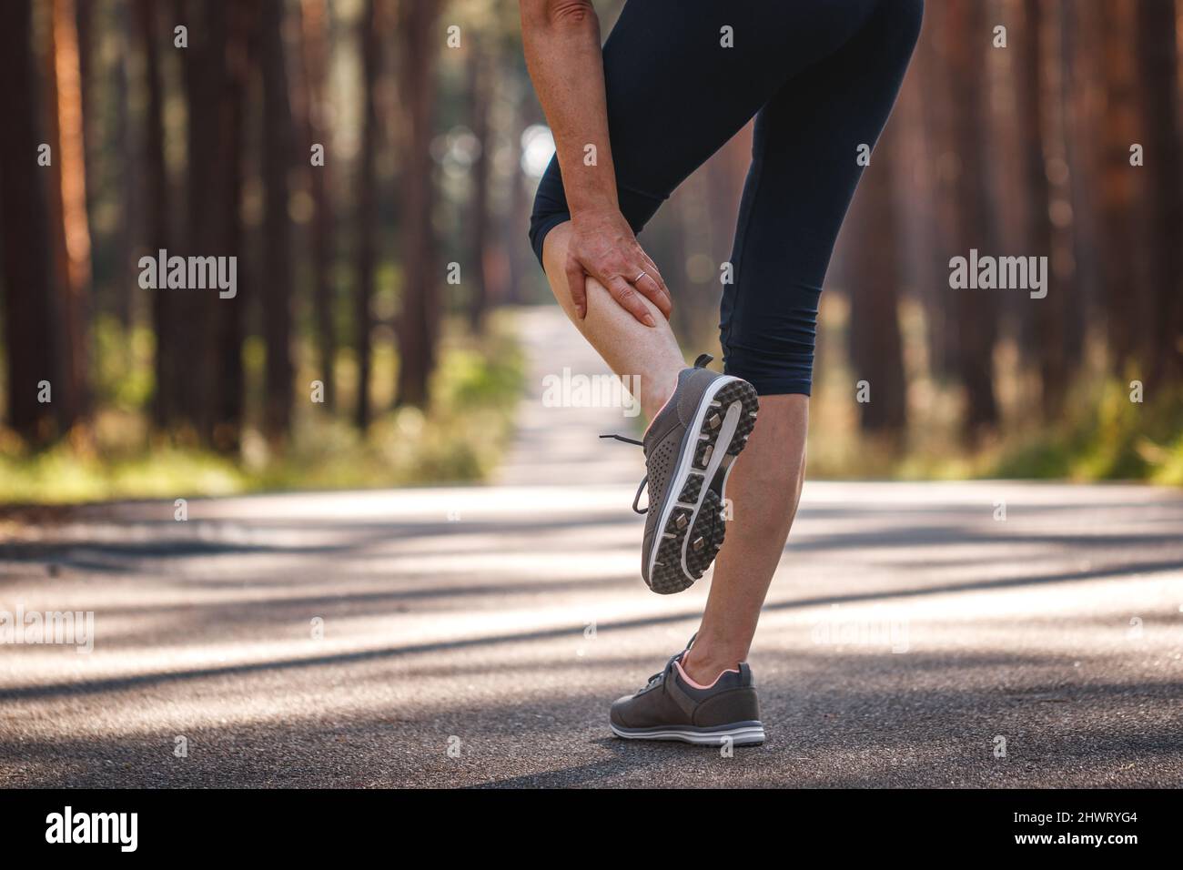 Donna che sente dolore alla gamba durante il jogging. Crampi muscolari di vitello. Sottostimare l'esercizio di riscaldamento prima di correre Foto Stock