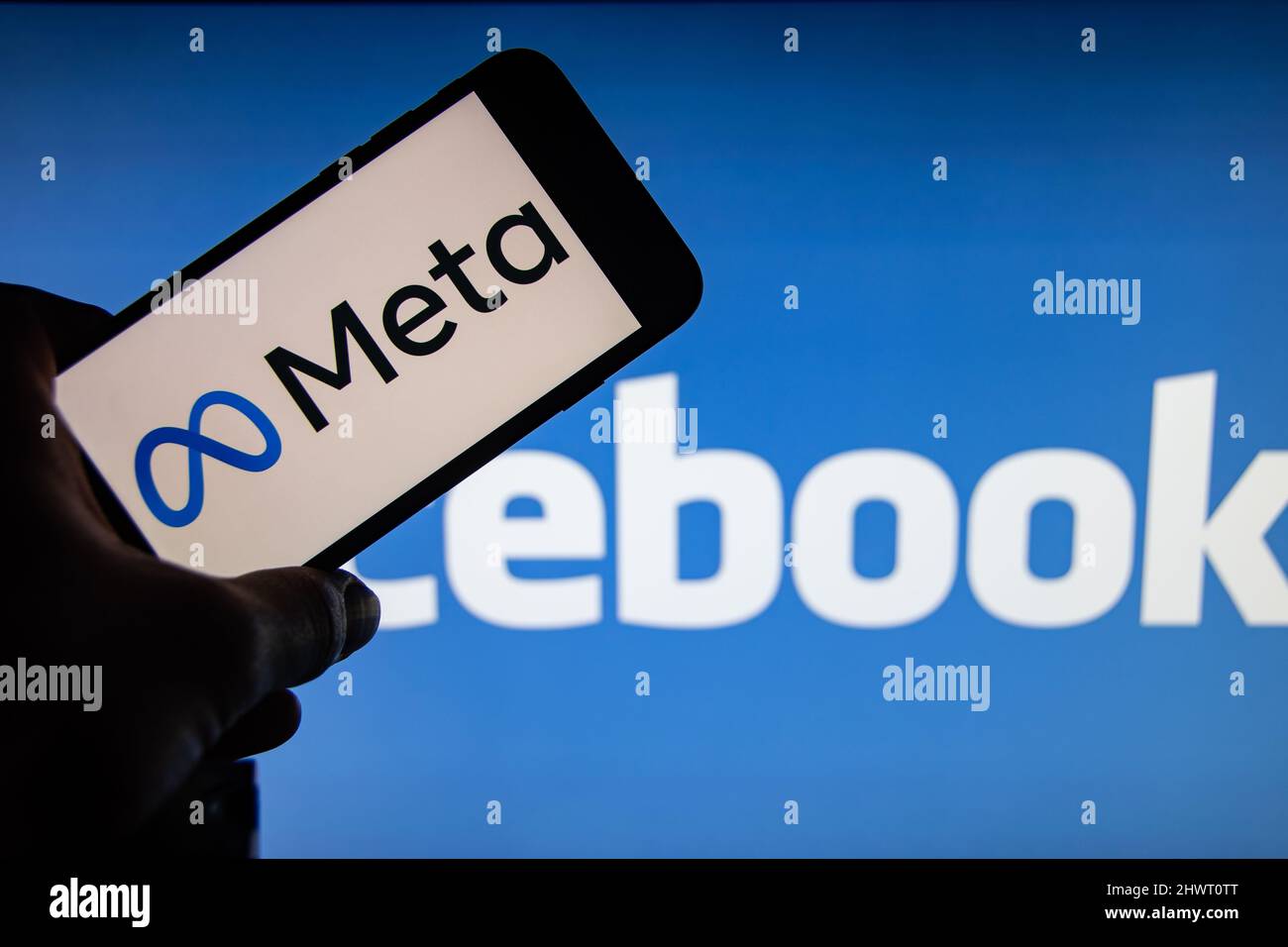 Rheinbach, Germania 30 ottobre 2021, il logo del marchio 'Meta' sul display di uno smartphone di fronte al logo Facebook.Facebook cambia nome Foto Stock