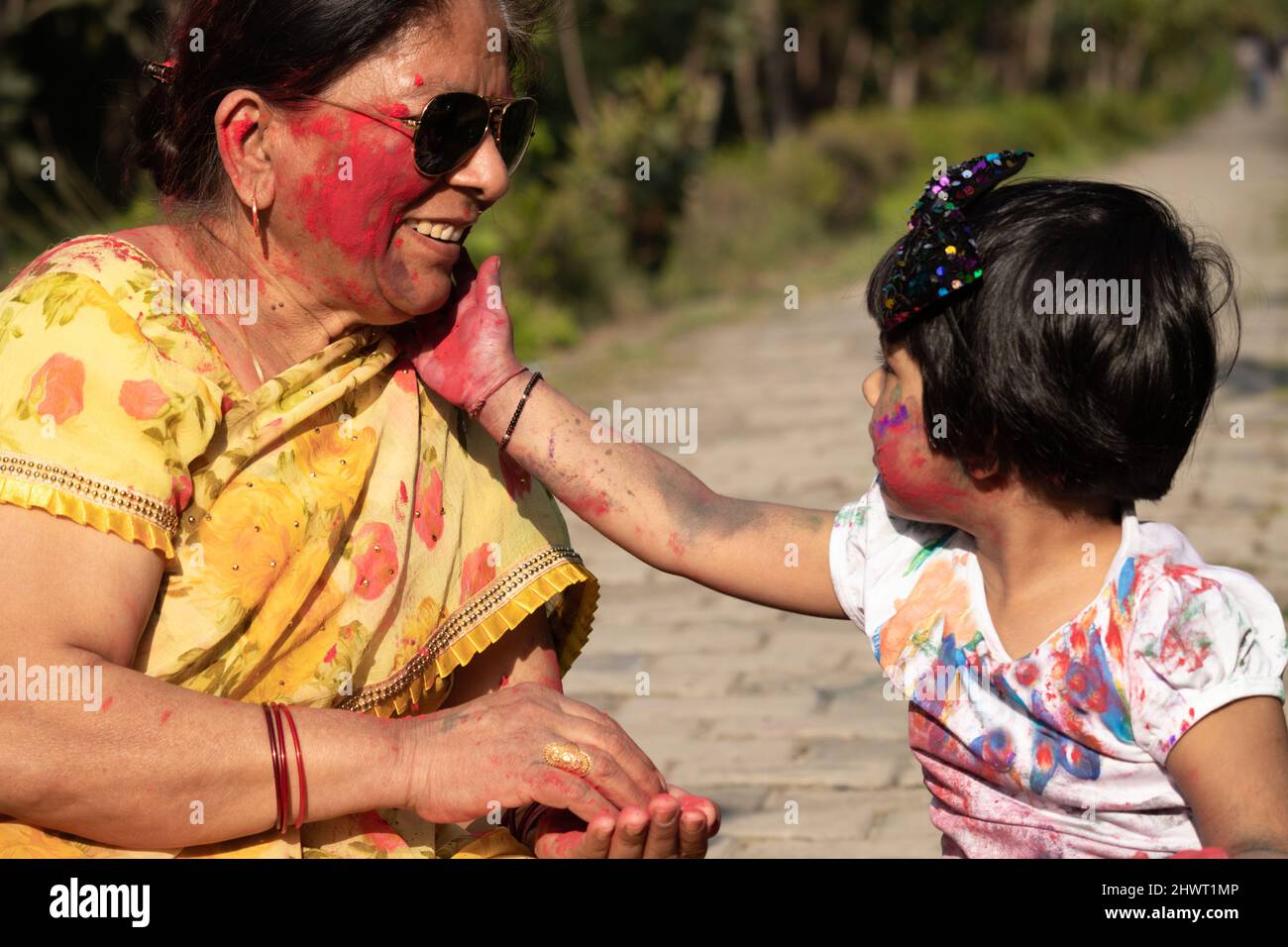 Anziana Signora indiana e Kid godendo Holi con Gulal o Abir Rang Aber. Festivo, Famiglia, Divertimento, Celebrazione, divertimento, Insieme, Multi Generation Foto Stock