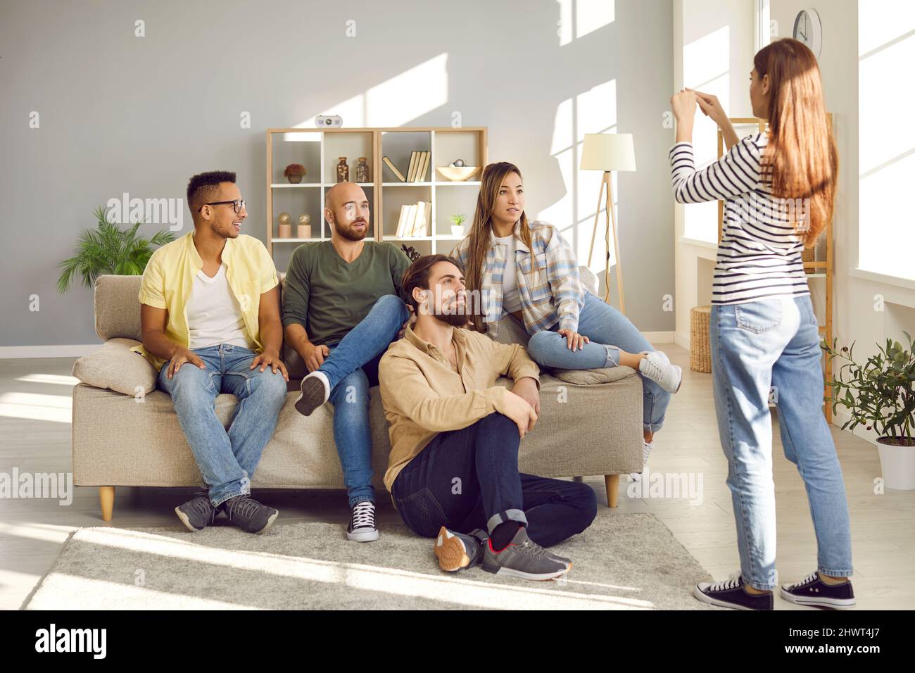 Gruppo di giovani migliori amici cercare di indovinare la parola giocando charades durante la festa a casa. Foto Stock