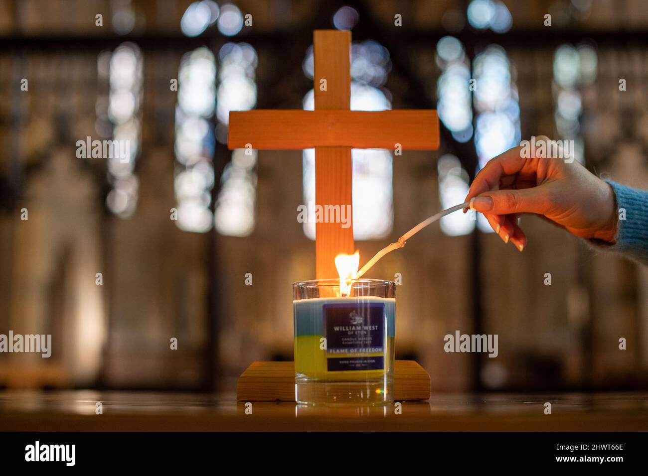 Windsor, Berkshire, Regno Unito. 7th marzo 2022. 35 anni la linea di Olga di origine Ucraina accende una candela nella chiesa parrocchiale di Windsor - Chiesa di San Giovanni Battista. La famiglia di Olga è intrappolata a Kiev ed è troppo pericoloso per loro andarsene. Olga che vive a Windsor con suo marito Roger, sta facendo a mano le candele Flame of Freedom nei colori della bandiera Ucraina per raccogliere fondi urgenti per aiuti umanitari per gli ucraini. Le candele sono in vendita via William West Candles e non sono a scopo di lucro. Credit: Maureen McLean/Alamy Live News Foto Stock