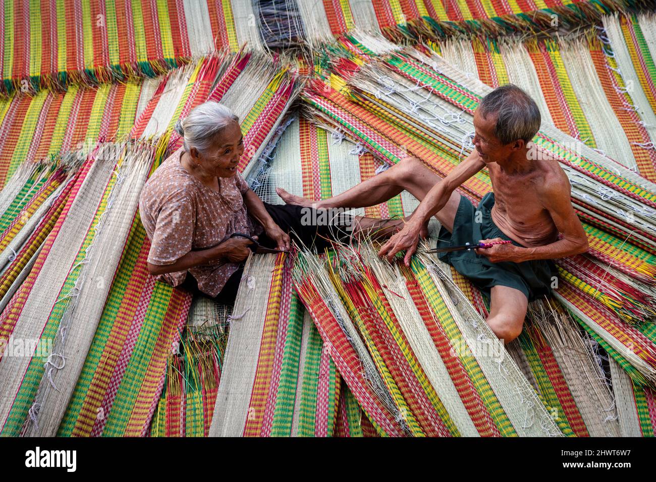 Vietnamita Old Man e le donne che fanno un asciugando tradizionale vietnam stuoie nel vecchio villaggio tradizionale a dinh Yen, dong thap, vietnam, artista di tradizione Foto Stock