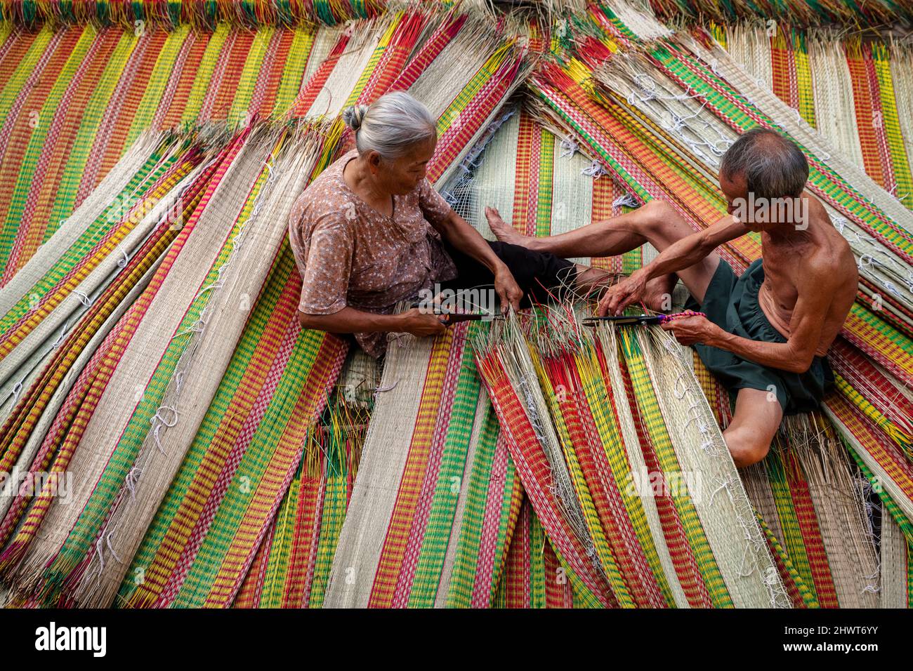 Vietnamita Old Man e le donne che fanno un asciugando tradizionale vietnam stuoie nel vecchio villaggio tradizionale a dinh Yen, dong thap, vietnam, artista di tradizione Foto Stock