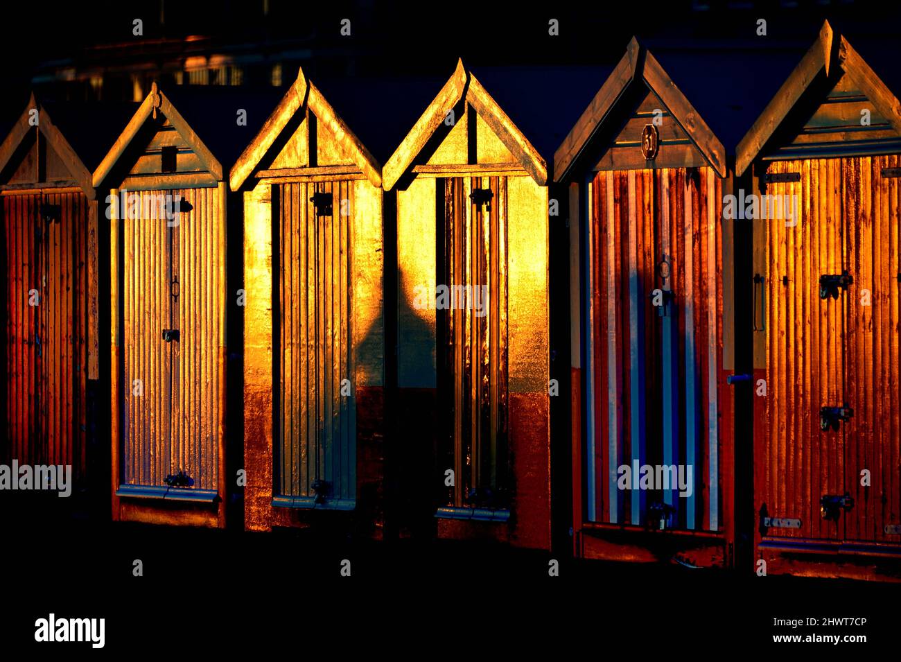 Le capanne sulla spiaggia si illuminano al tramonto Foto Stock