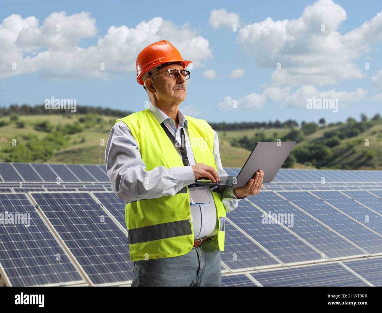 Ingegnere maschio maturo che lavora con un laptop su un campo fotovoltaico pannelli solari Foto Stock