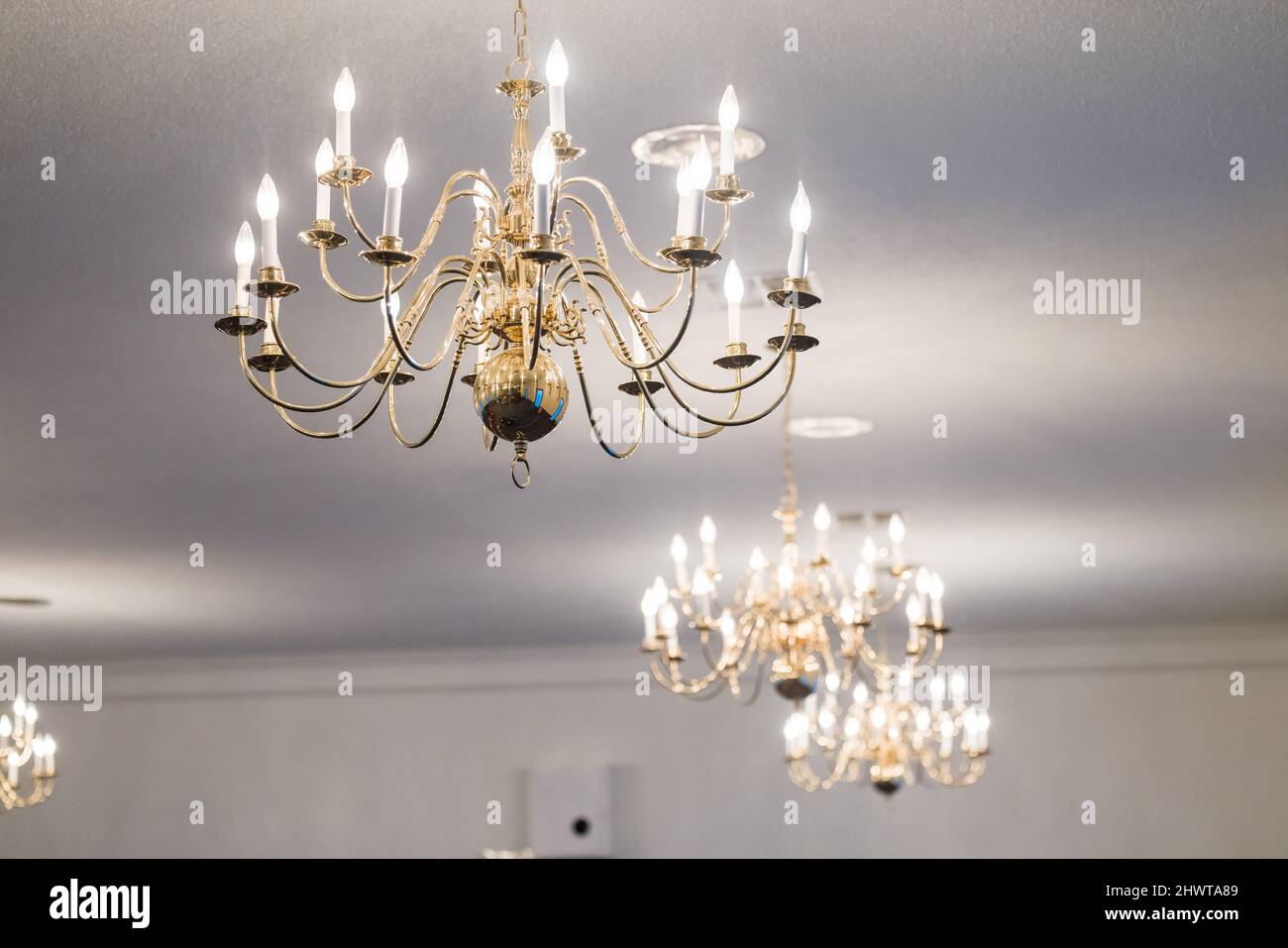 Diverse luci a candeliere appese a un soffitto bianco per illuminare una stanza Foto Stock