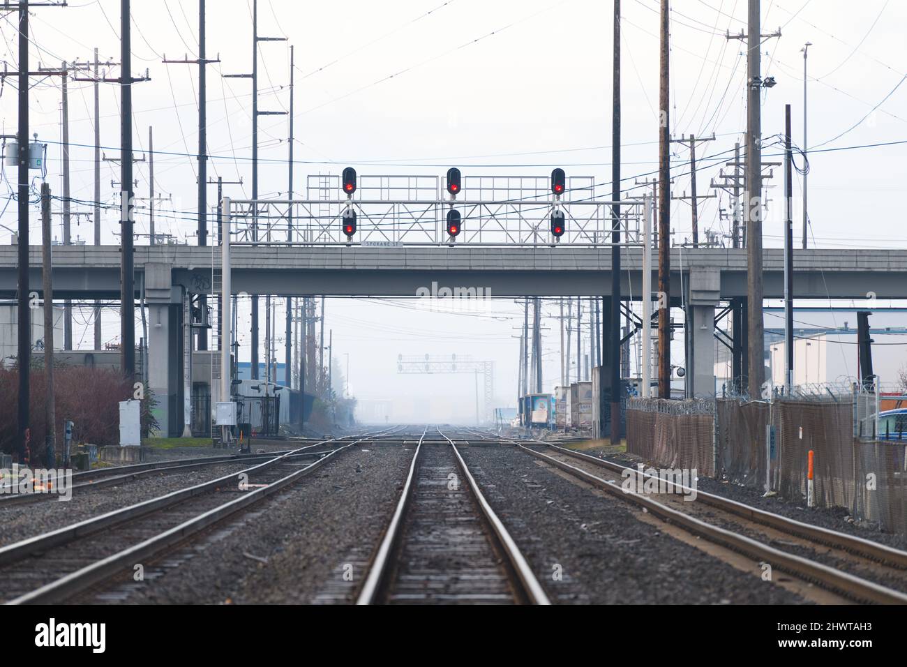 I binari del treno nella nebbia passano sotto il Viadotto di Spokane Street a Seattle, tutti gli indicatori luminosi a rosso e nessun treno Foto Stock