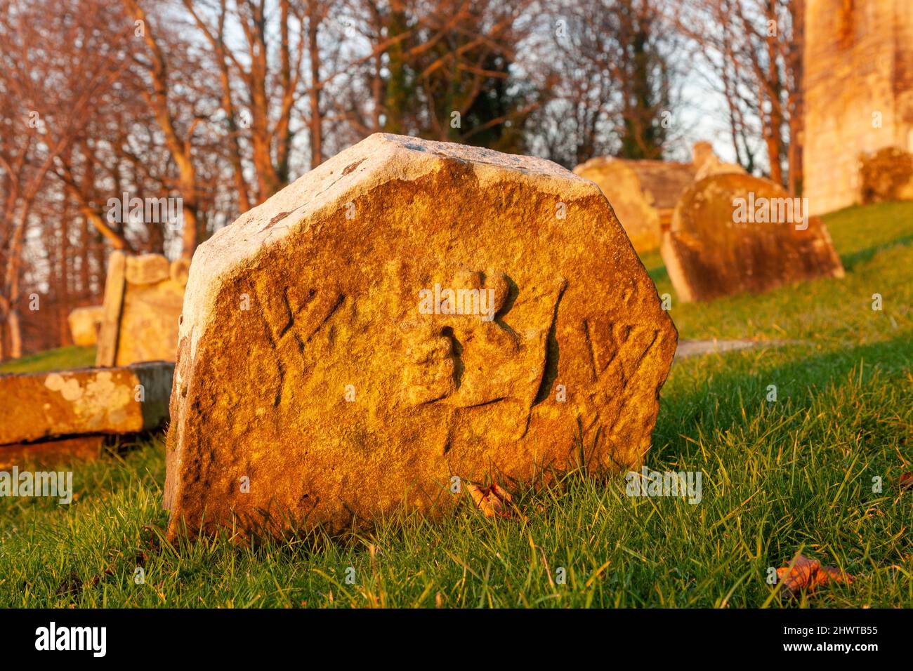 Una vecchia tomba con una mano scolpita che tiene un oggetto, la chiesa di St Bridgets Kirk, Dalgety Bay, Scozia Foto Stock