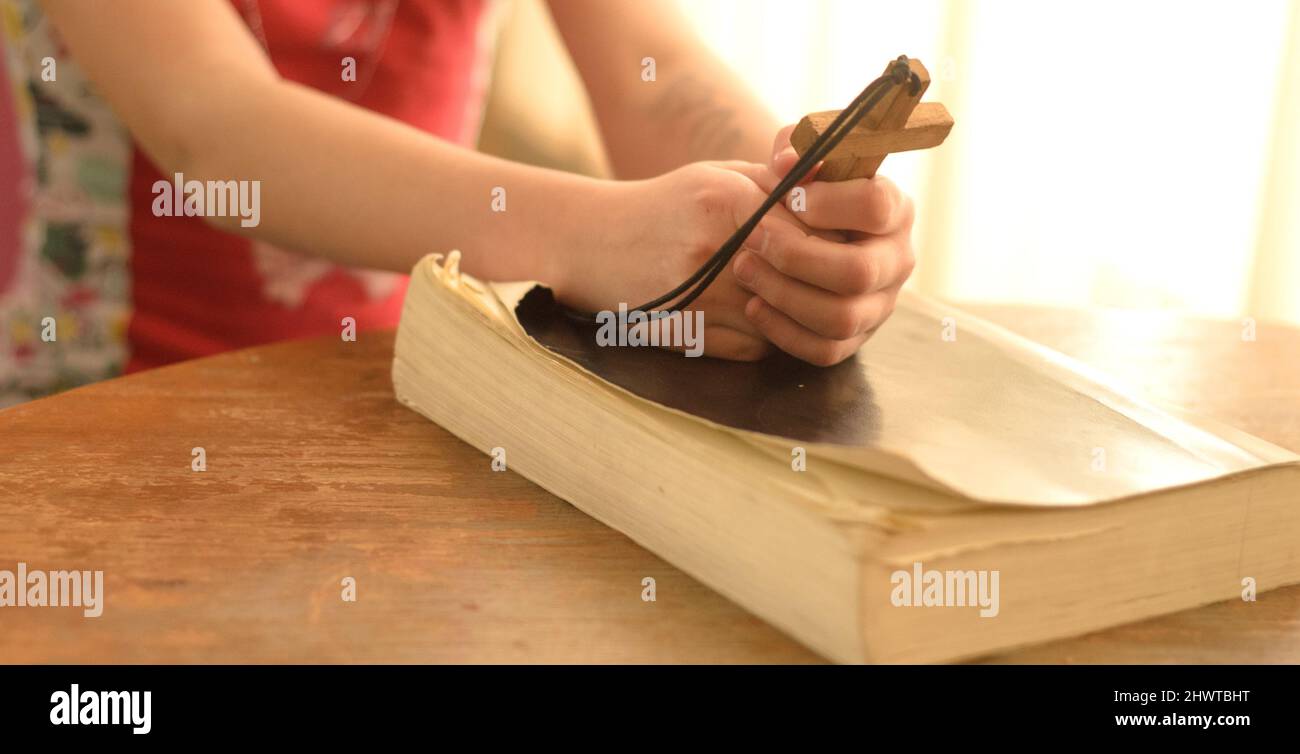 Ragazza adolescente che prega a Dio tenendo una croce di legno. Foto Stock