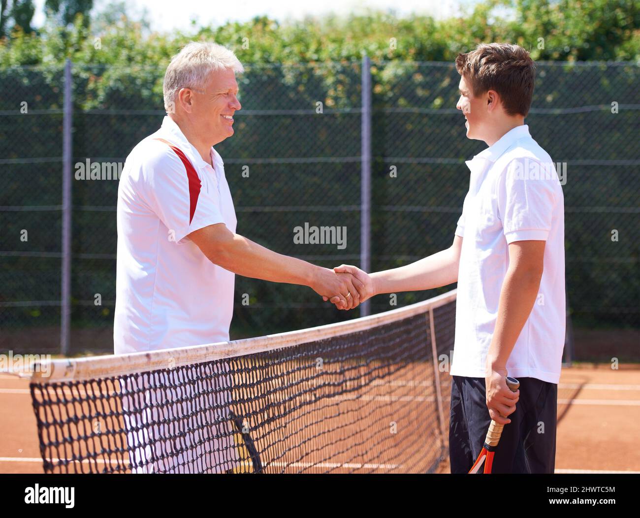 Buon figlio del gioco. Un padre e un figlio scuotono le mani dopo una partita amichevole di tennis. Foto Stock
