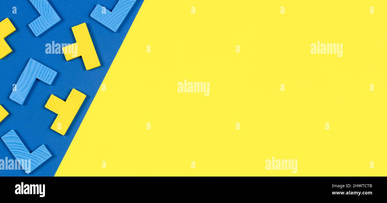 Diverse forme colorate blocchi di puzzle in legno su sfondo blu e giallo. Forme geometriche in diversi colori, vista dall'alto, spazio di copia Foto Stock