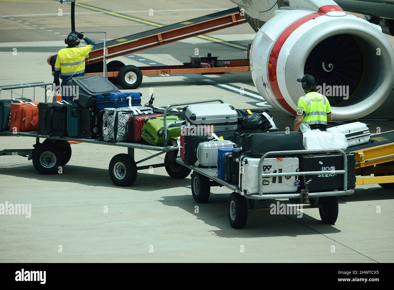 Il movimentatore di bagagli carica e scarica i bagagli su un aereo di linea commerciale in un aeroporto molto trafficato Foto Stock