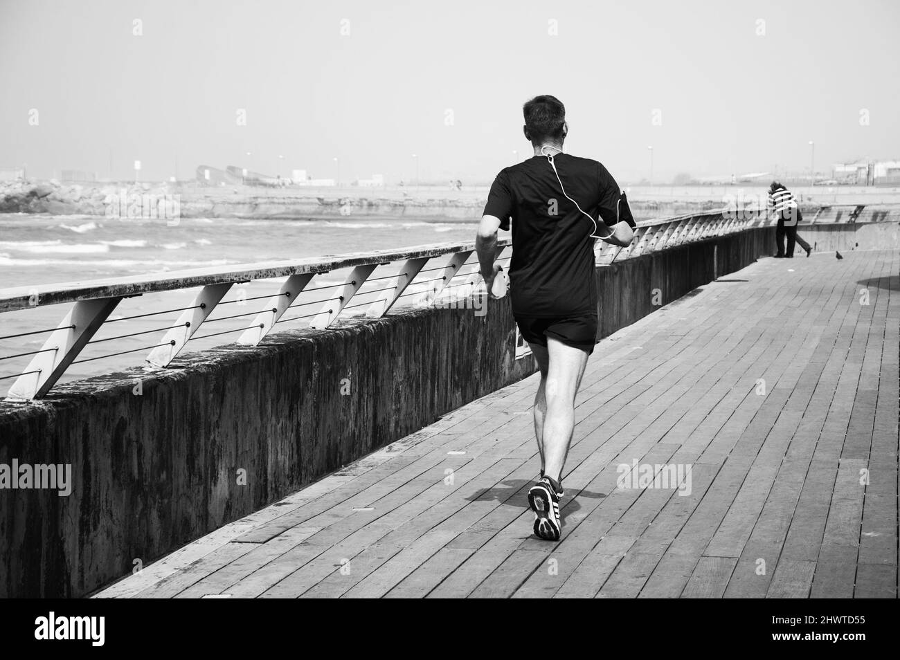 TEL AVIV-YAFO, ISRAELE - 24 FEBBRAIO 2014: Uomo di mezza età che fa jogging al Porto Vecchio di Tel Aviv. Il porto e' una popolare area ricreativa e commerciale. Bianco nero Foto Stock