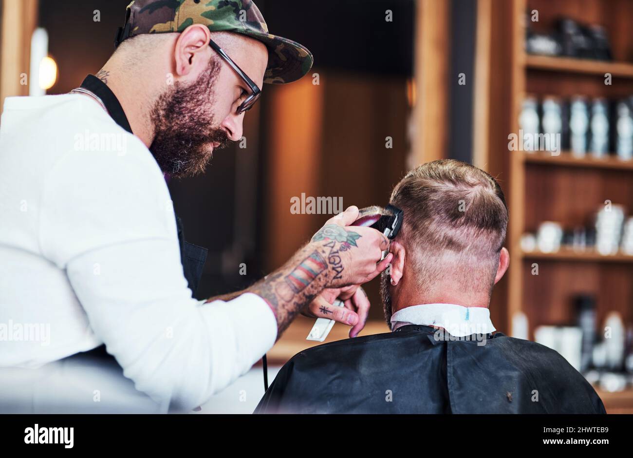 Ogni acconciatura racconta una storia. Scatto corto di un bel giovane barbiere che dà un taglio di capelli al cliente all'interno del suo barbiere. Foto Stock