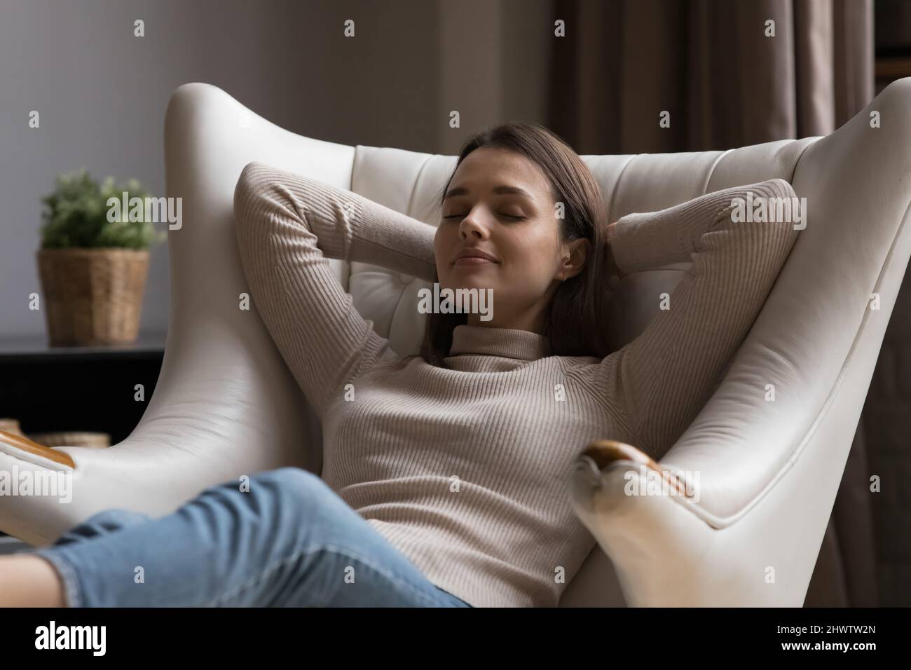 Serena giovane donna relax appoggiata su una comoda poltrona Foto Stock