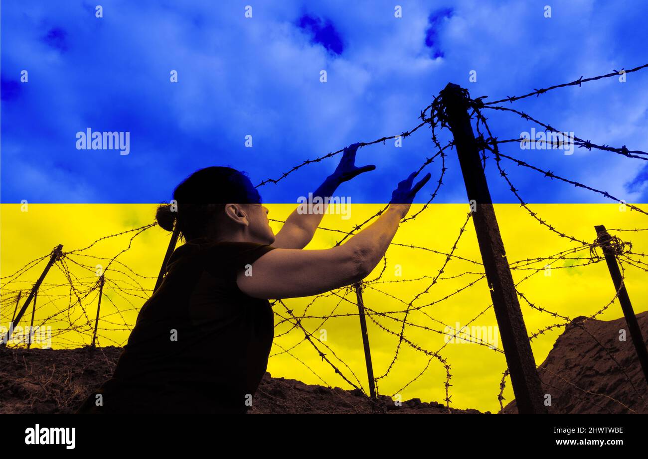 Donna che guarda sopra recinzione filo spinato con bandiera di Ucraina sovrastata. Russia Ucraina conflitto, guerra, rifugiati, rifugiati, attraversamento delle frontiere, UE, Europa Foto Stock