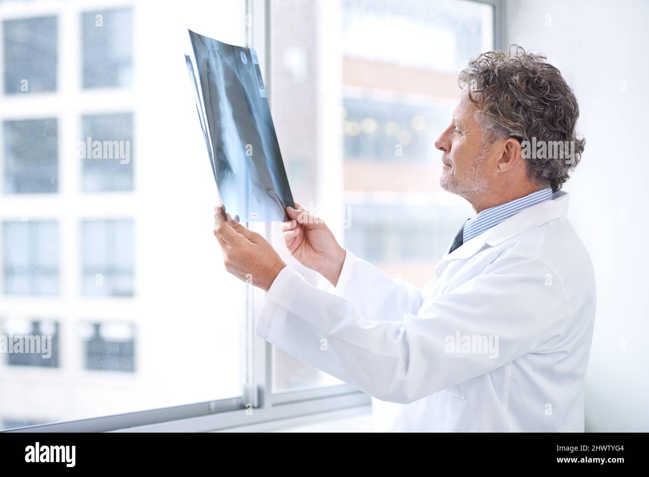 HES ha ottenuto le informazioni interne alla vostra salute. Shot di un medico maturo che esamina una radiografia nel suo ufficio. Foto Stock