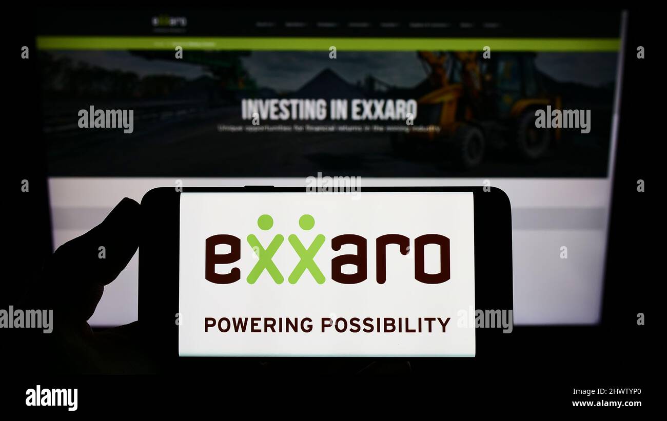 Persona che tiene smartphone con il logo della società sudafricana Exxaro Resources Limited sullo schermo di fronte al sito web. Mettere a fuoco sul display del telefono. Foto Stock