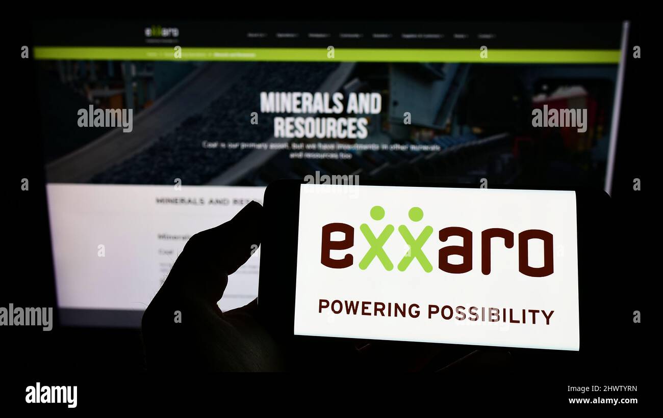 Persona che tiene il cellulare con il logo della società sudafricana Exxaro Resources Limited sullo schermo di fronte al sito web. Mettere a fuoco sul display del telefono. Foto Stock