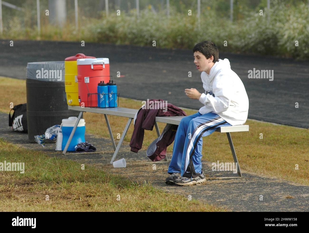 Partita di calcio di 11 e 12 anni giocatori che stanno perdendo e la stella QB è ferita e seduta sul banco di osservazione e non fare nulla per aiutare Foto Stock