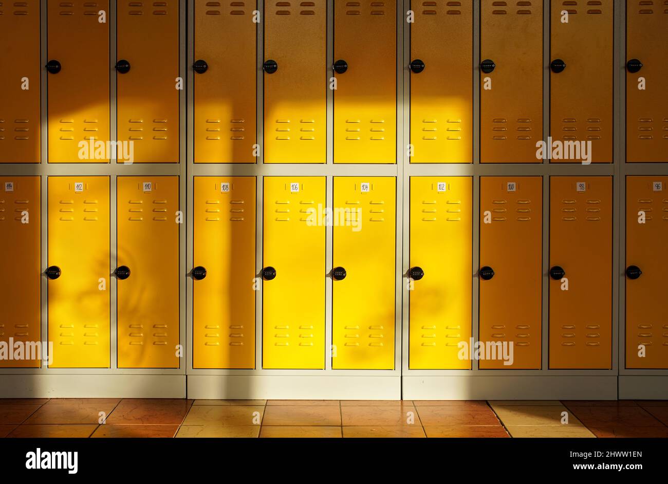 Il sole splende su una sala scuola elementare vuota, armadietti numerati al muro Foto Stock
