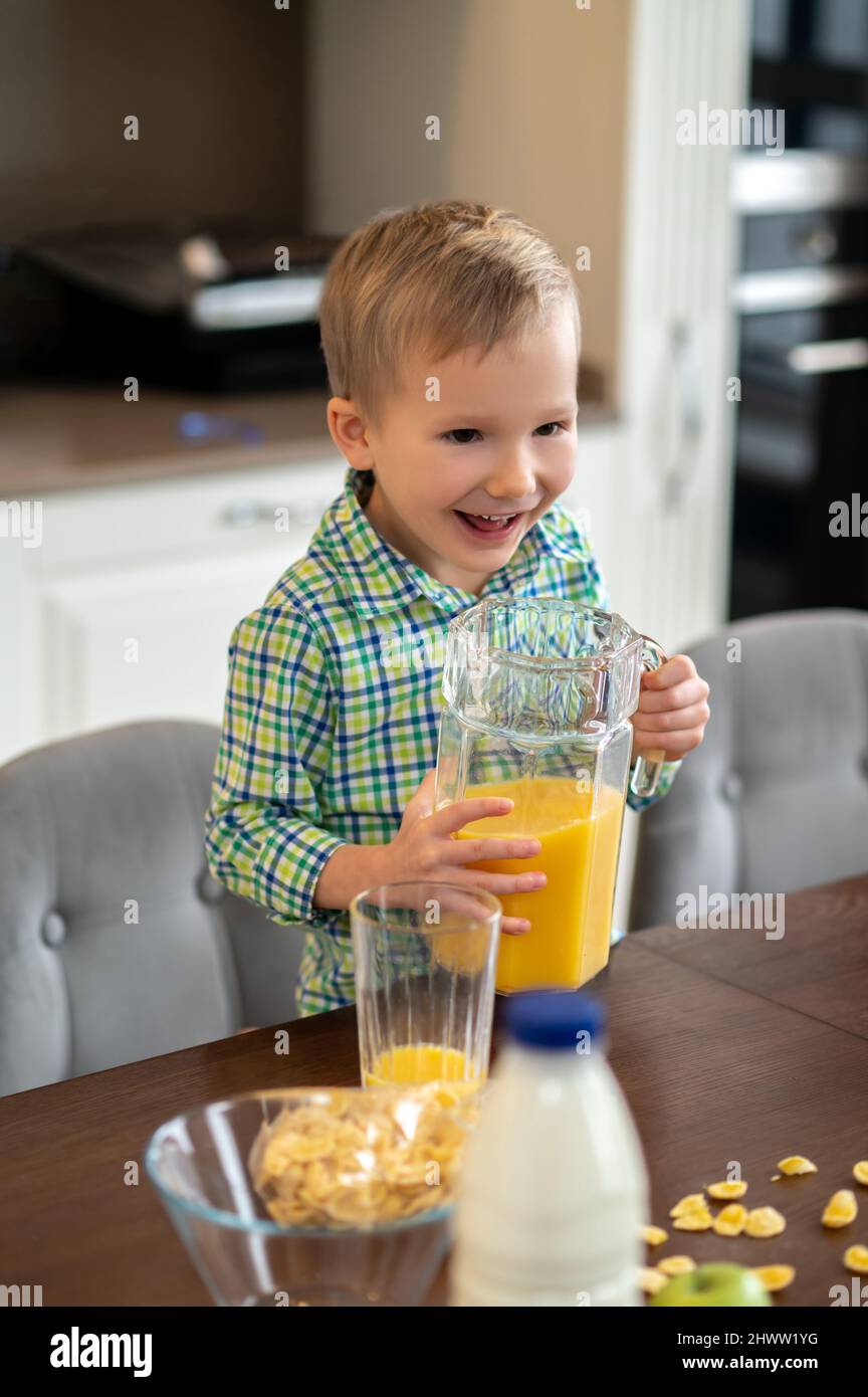 Il bambino è contento di una caraffa di vetro in cucina Foto Stock