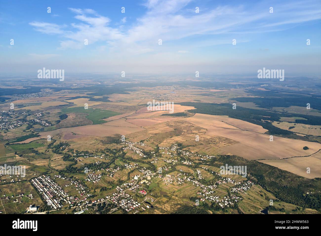 Vista aerea di campi agricoli e case sparse in lontananza in zona rurale. Foto Stock