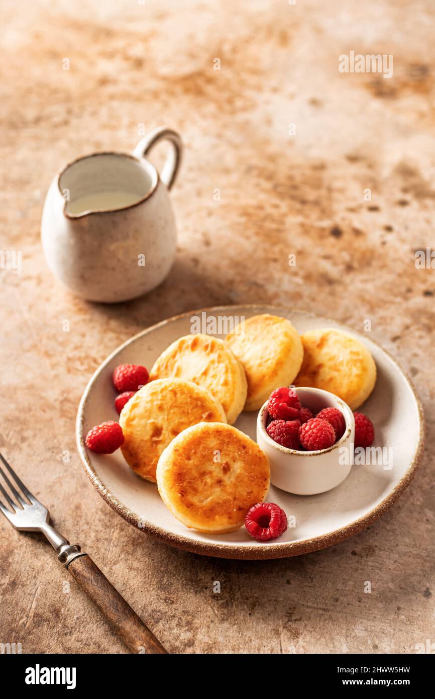 Pancake al formaggio casolare, sciroppi con lampone fresco su sfondo testurizzato Foto Stock
