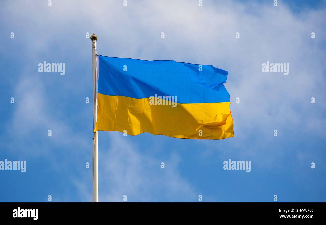 Bandiera Ucraina, su flagpole volando e svolazzando al sole con sfondo di nuvola e cielo blu Foto Stock