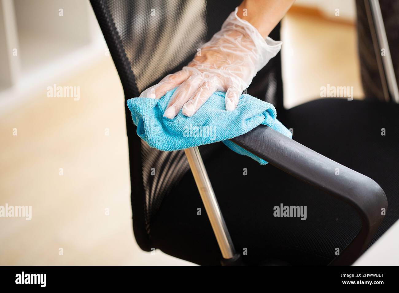 Donna strofinare i mobili in ufficio con un panno disinfettante umido Foto Stock