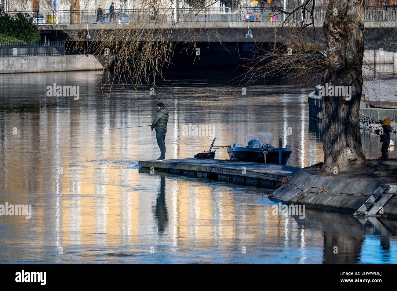 Uomo che pesca al fiume Motala a Norrkoping durante la primavera iniziale. Norrkoping è una storica città industriale svedese. Foto Stock