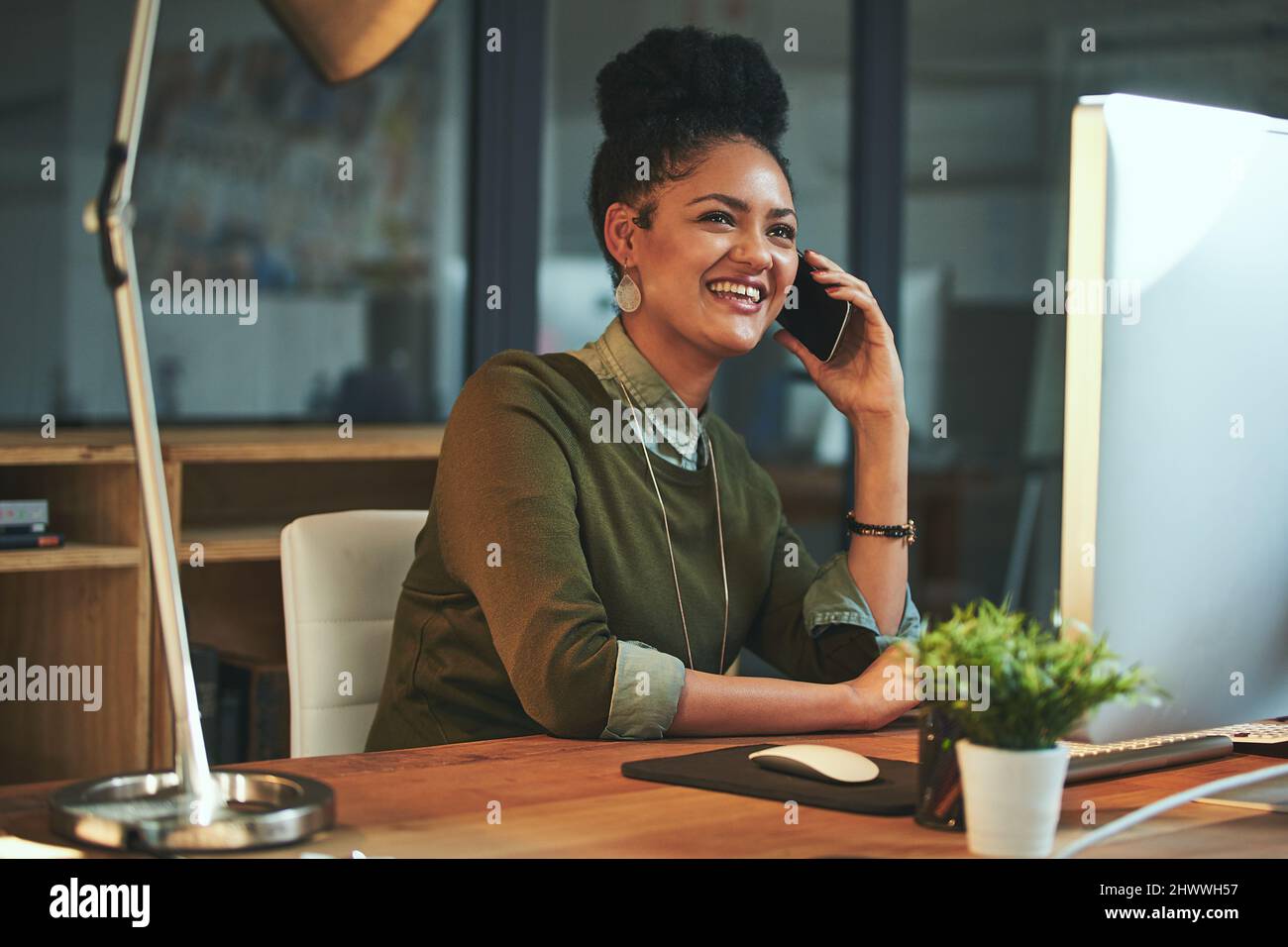 Basta chiamare per farvi sapere che sarà in ritardo. Scatto di una giovane donna attraente usando il suo cellulare in ufficio. Foto Stock
