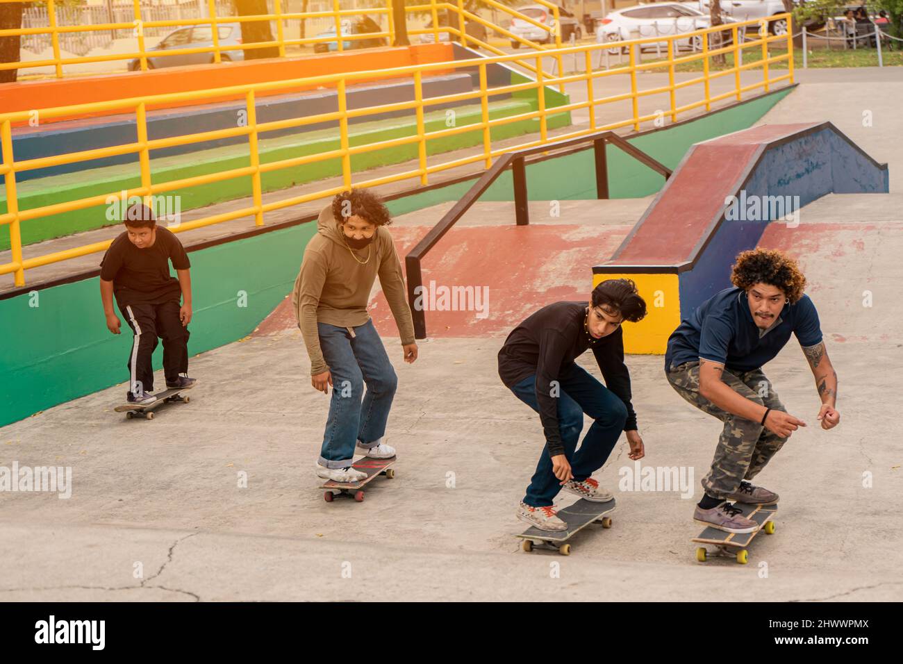 Gruppo di giovani pattinatori che scivolano per saltare su una rampa in un parco skate Foto Stock