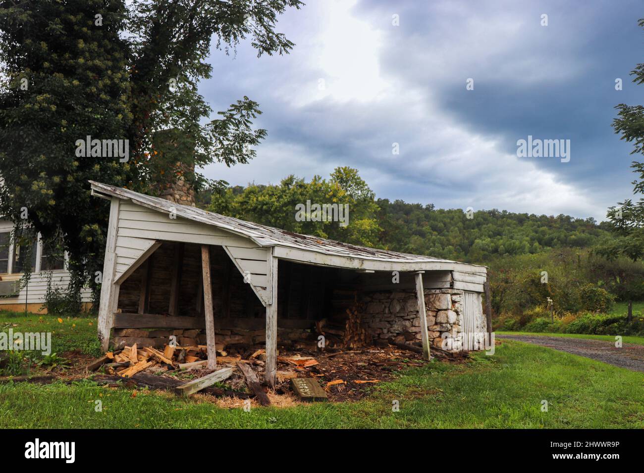 Un capannone di legno pendente mantiene il legno tritato asciutto in un giorno piovoso in una fattoria nelle colline della Virginia rurale. Foto Stock